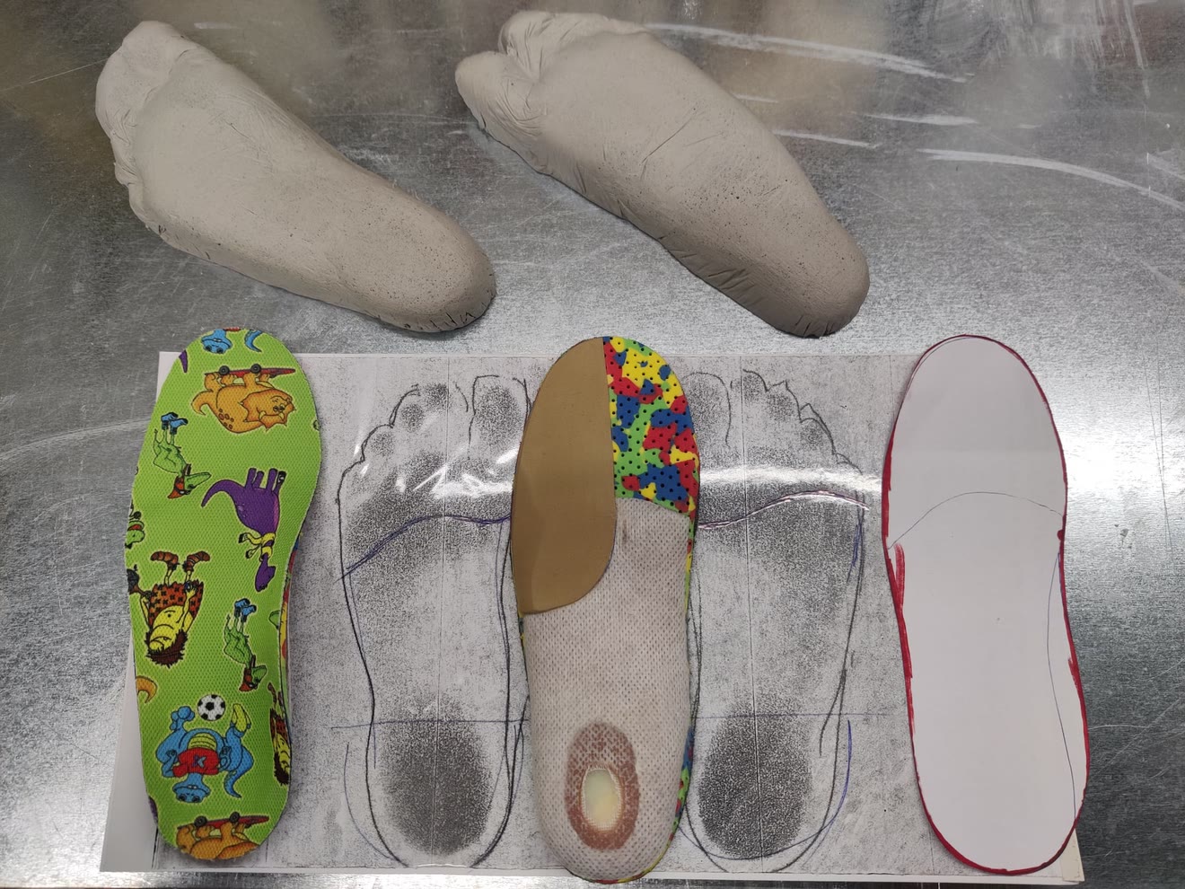Calchi in gesso, foglio di rilievo dell’impronta e plantari pediatrici sul banco di lavoro